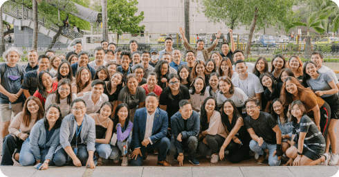 A large, energetic group photo of the diverse Coins.ph fintech team posing together outdoors, capturing the collaborative culture and growing community of #TeamCoins